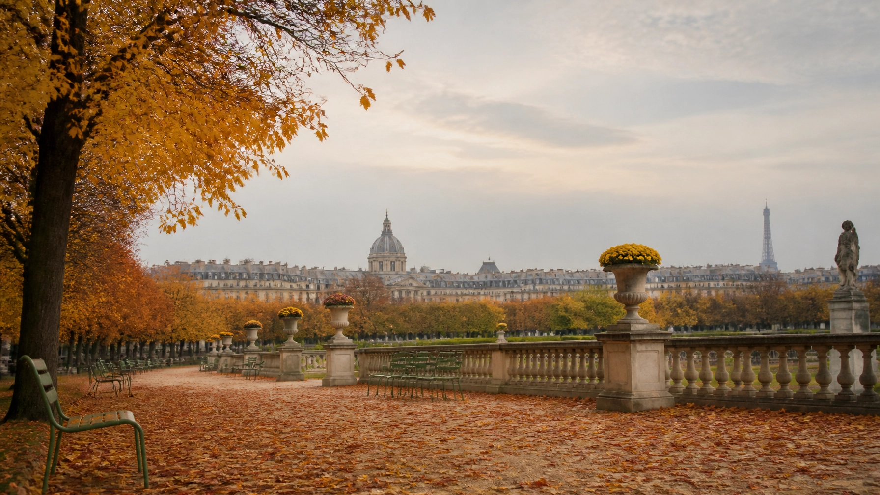 Golden autumn leaves covering a path in a Parisian park with classic architecture in the distance