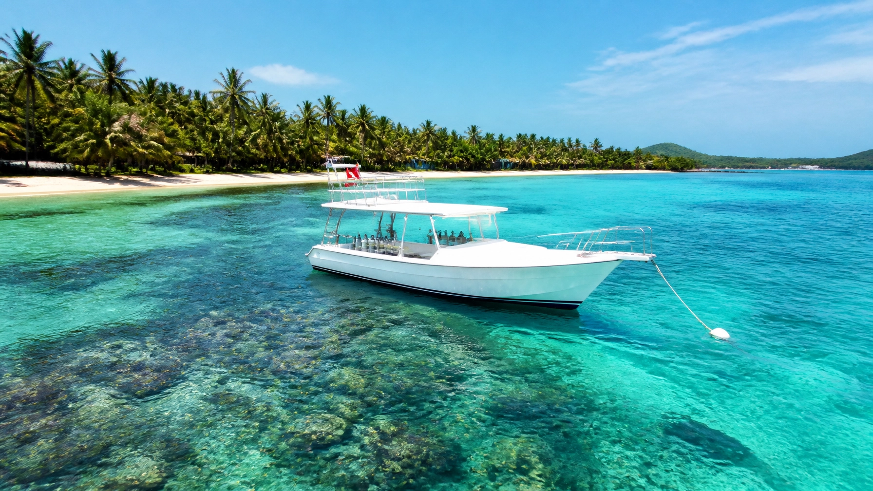 Crystal clear turquoise bay in Roatan with a dive boat and tropical palms